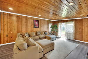 Living area featuring wooden walls, recessed lighting, and wood finished floors