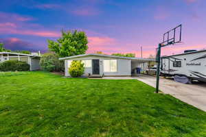 View of front of house with an attached carport, driveway, and a lawn