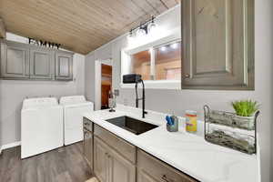 Laundry area with a vaulted wooden ceiling, washing machine and dryer, dark wood-type flooring, and cabinet space