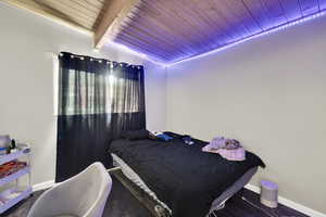 Bedroom featuring a wood ceiling with exposed beams and baseboards
