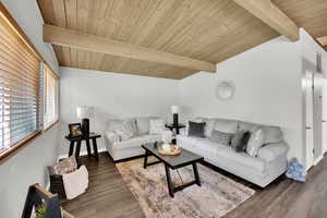 Living area with wooden ceiling, vaulted ceiling with beams, and wood finished floors