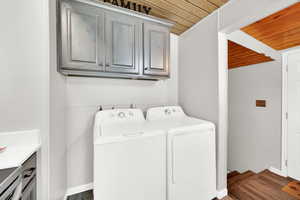 Laundry area featuring wood ceiling, cabinet space, dark wood-style floors, and washer and dryer