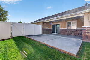 Rear view of house featuring a gate, brick siding, and roof with shingles