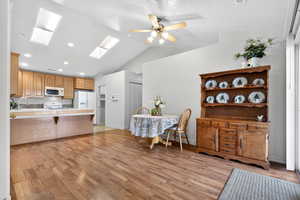 Kitchen with a skylight, light countertops, a peninsula, a kitchen bar, and light wood-style floors