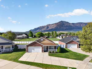 View of front of house with concrete driveway, brick siding, an attached garage, a mountain view, and a residential view