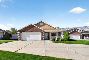 Single story home featuring a garage, concrete driveway, brick siding, a front lawn, and a porch