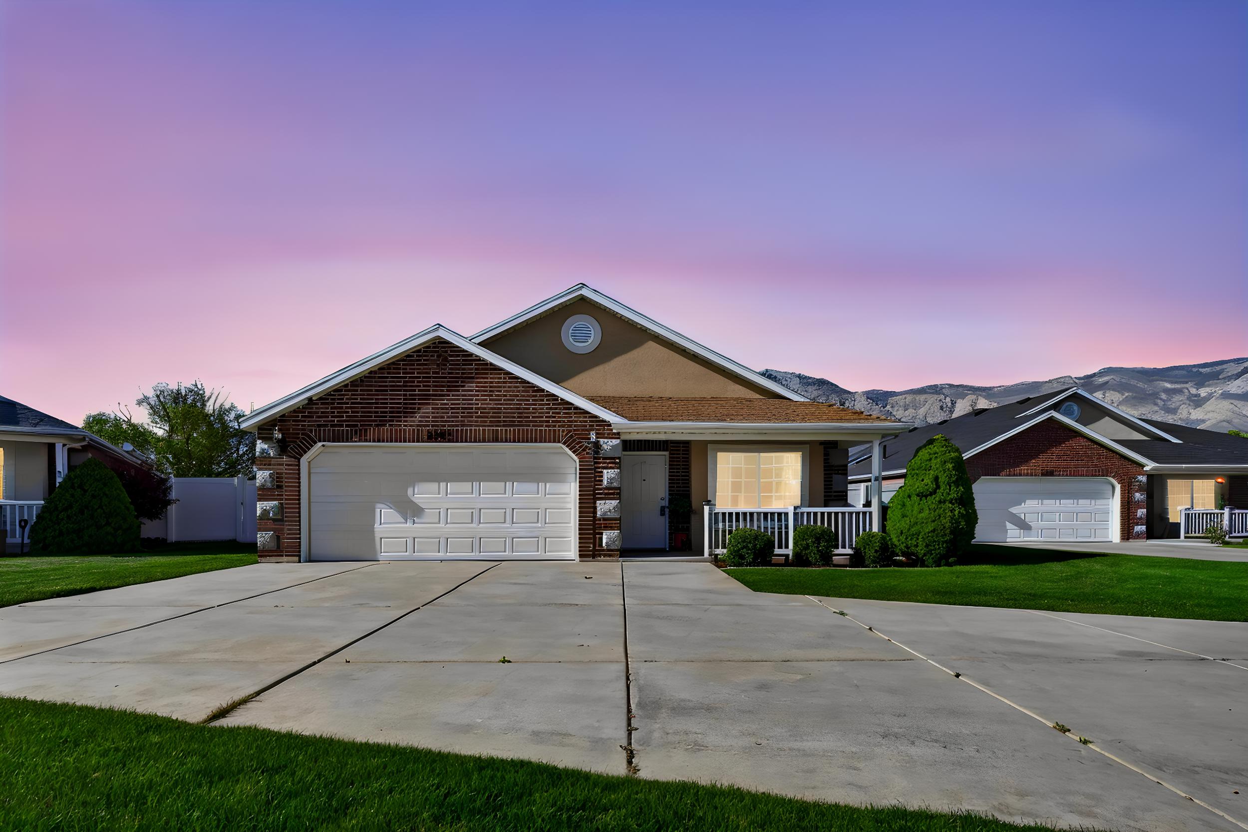 Ranch-style house featuring concrete driveway, brick siding, an attached garage, and a lawn