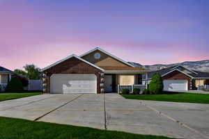 Ranch-style house featuring concrete driveway, brick siding, an attached garage, and a lawn