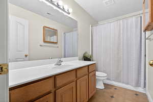 Bathroom featuring vanity, dark tile patterned flooring, and a textured ceiling
