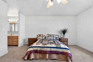 Bedroom with light colored carpet, ceiling fan, and a textured ceiling