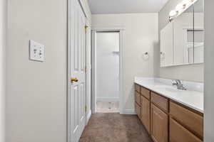 Bathroom featuring vanity, a textured ceiling, and dark carpet