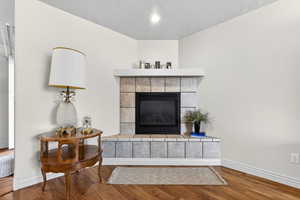 Detailed view of wood finished floors, a tiled fireplace, and a textured ceiling