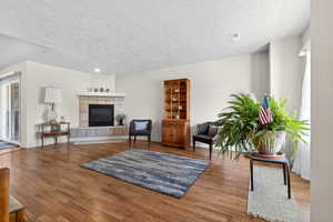 Living room featuring wood finished floors, a textured ceiling, and a tile fireplace