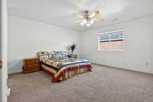 Carpeted bedroom with a ceiling fan and a textured ceiling