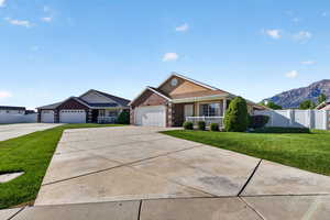 Single story home with brick siding, driveway, a garage, covered porch, and a mountain view