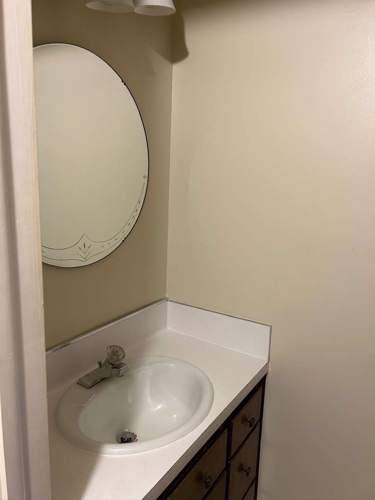 Vanity with integrated sink, white countertop, and dark wood-finish cabinetry featuring multiple drawers