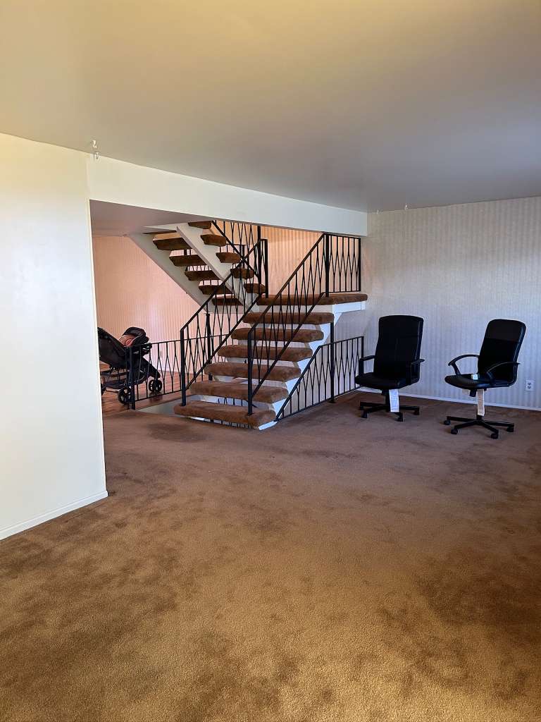Two-story interior featuring a carpeted staircase with wrought iron railings