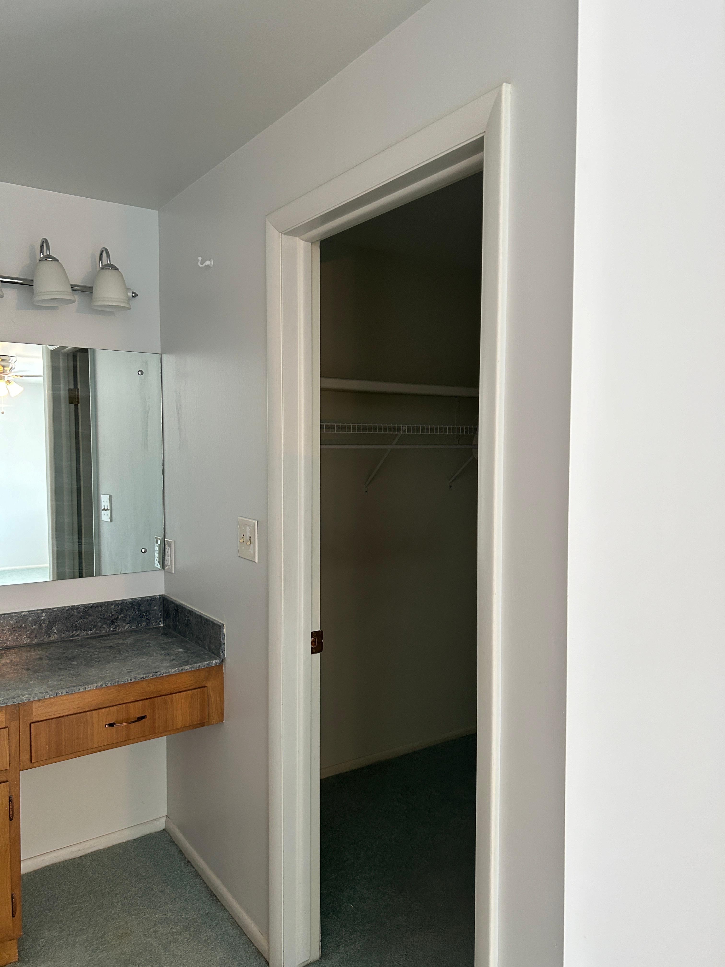 Built-in vanity with a stone-finish countertop and mirrored backsplash