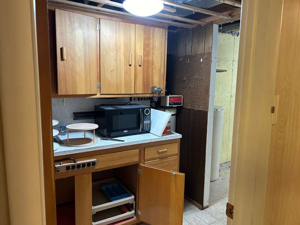 Compact kitchen area featuring wood cabinetry, a speckled countertop, and a built-in microwave space