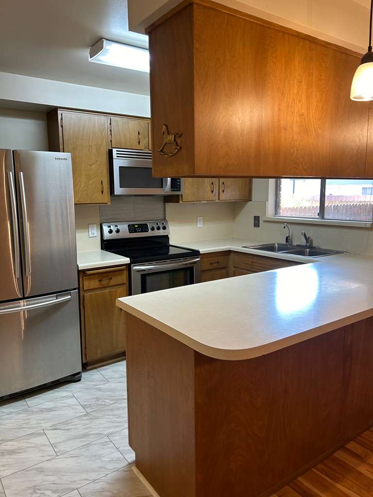 Kitchen featuring wood cabinetry, light-toned countertops, and stainless steel appliances