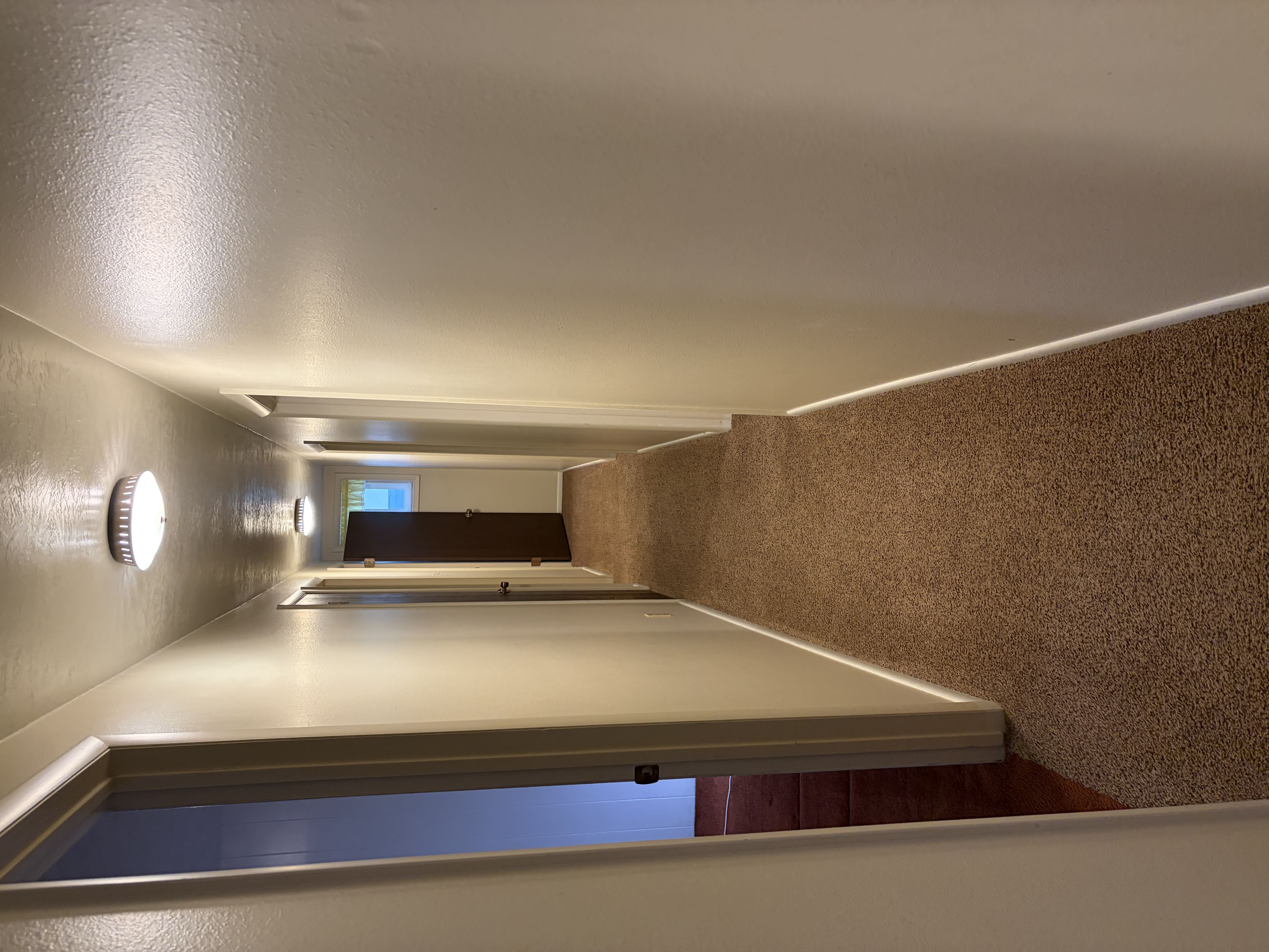 Hallway with carpet flooring and a textured wall