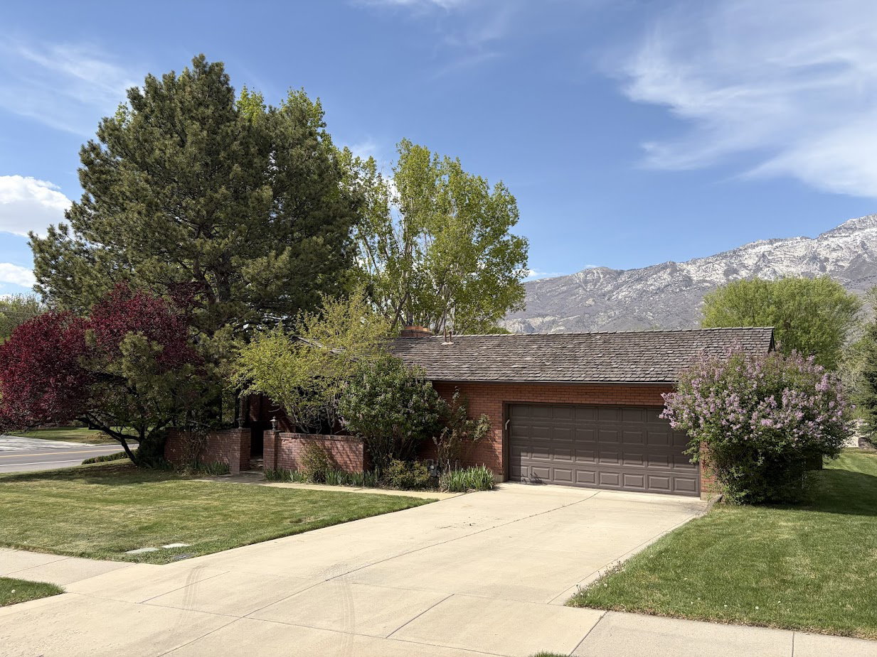 View of front of home featuring a front yard, driveway, an attached garage, and brick siding