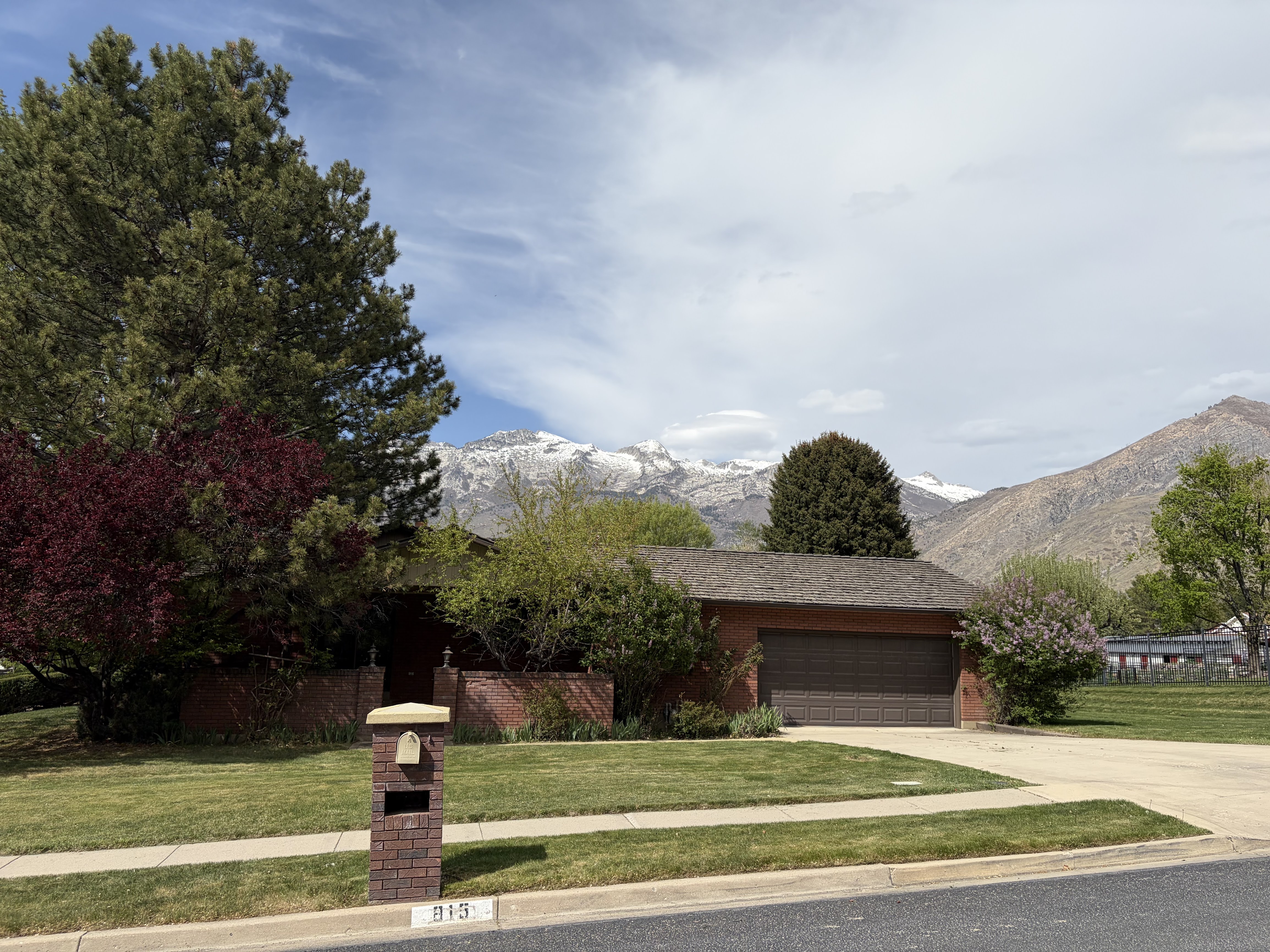 View of front of house featuring a front lawn, an attached garage, a mountain view, and concrete driveway