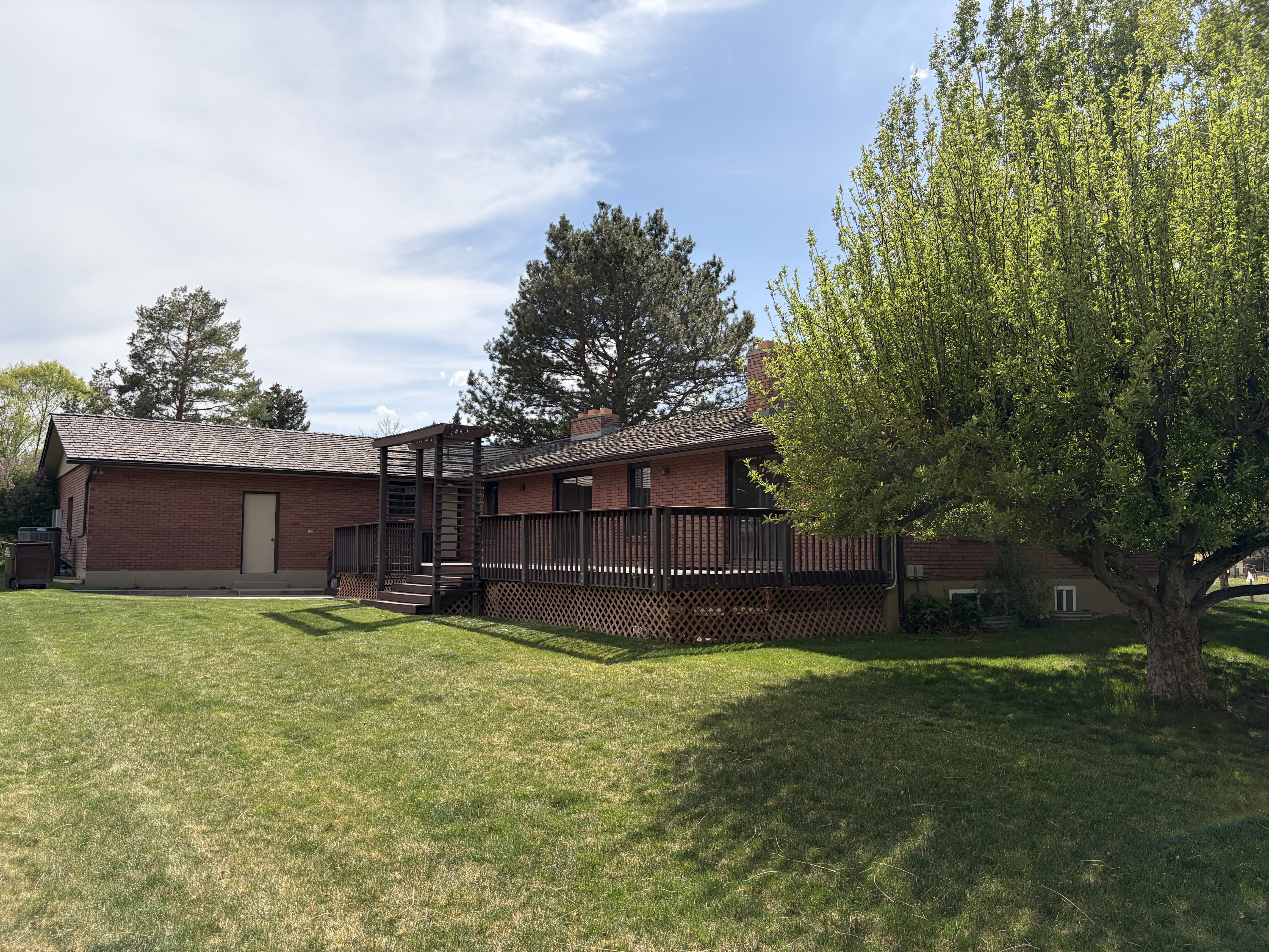 Rear view of property featuring brick siding, a yard, and a wooden deck