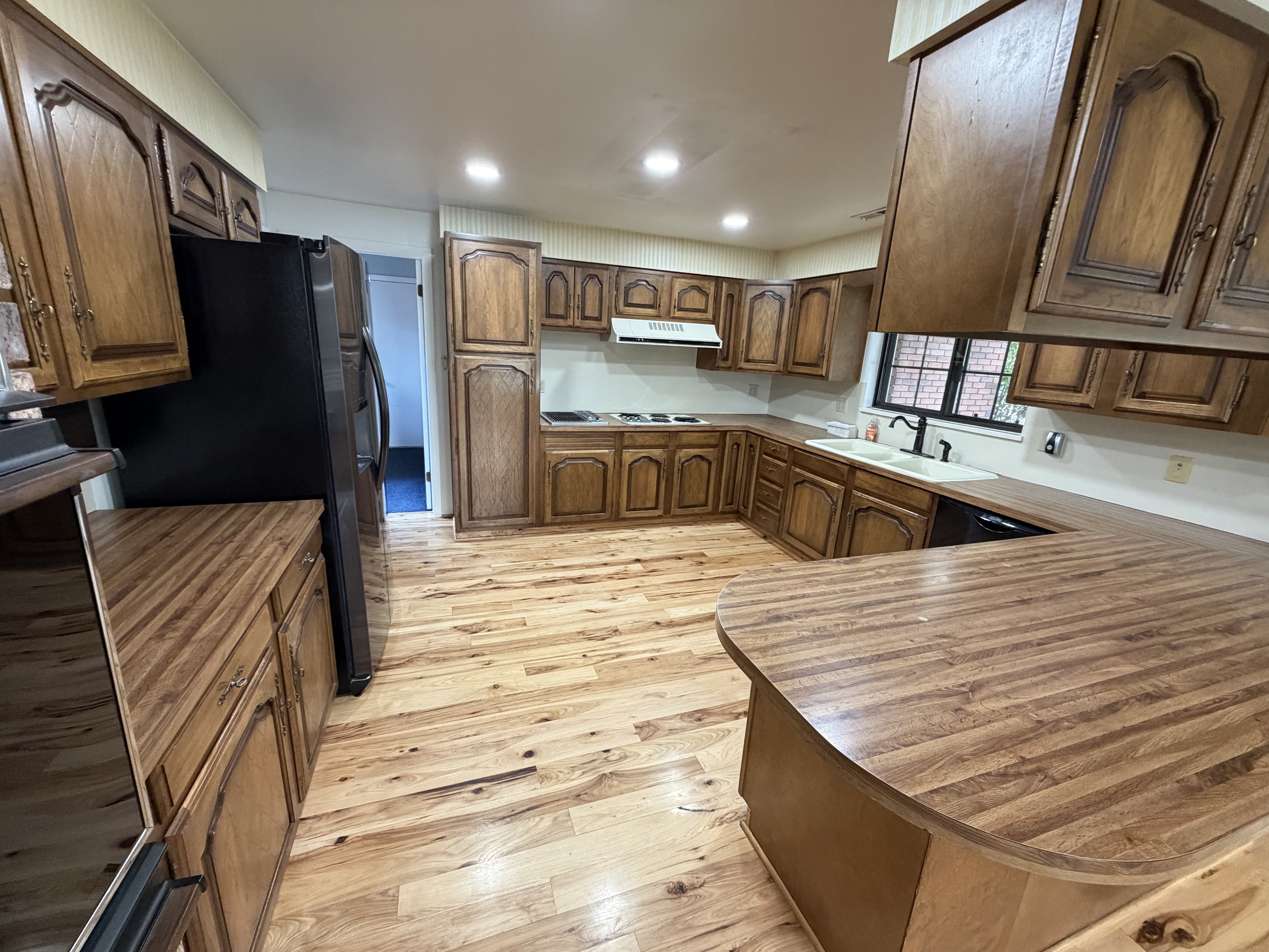 Kitchen featuring wood finish cabinetry, recessed lighting, a peninsula, light wood finished floors, and black appliances