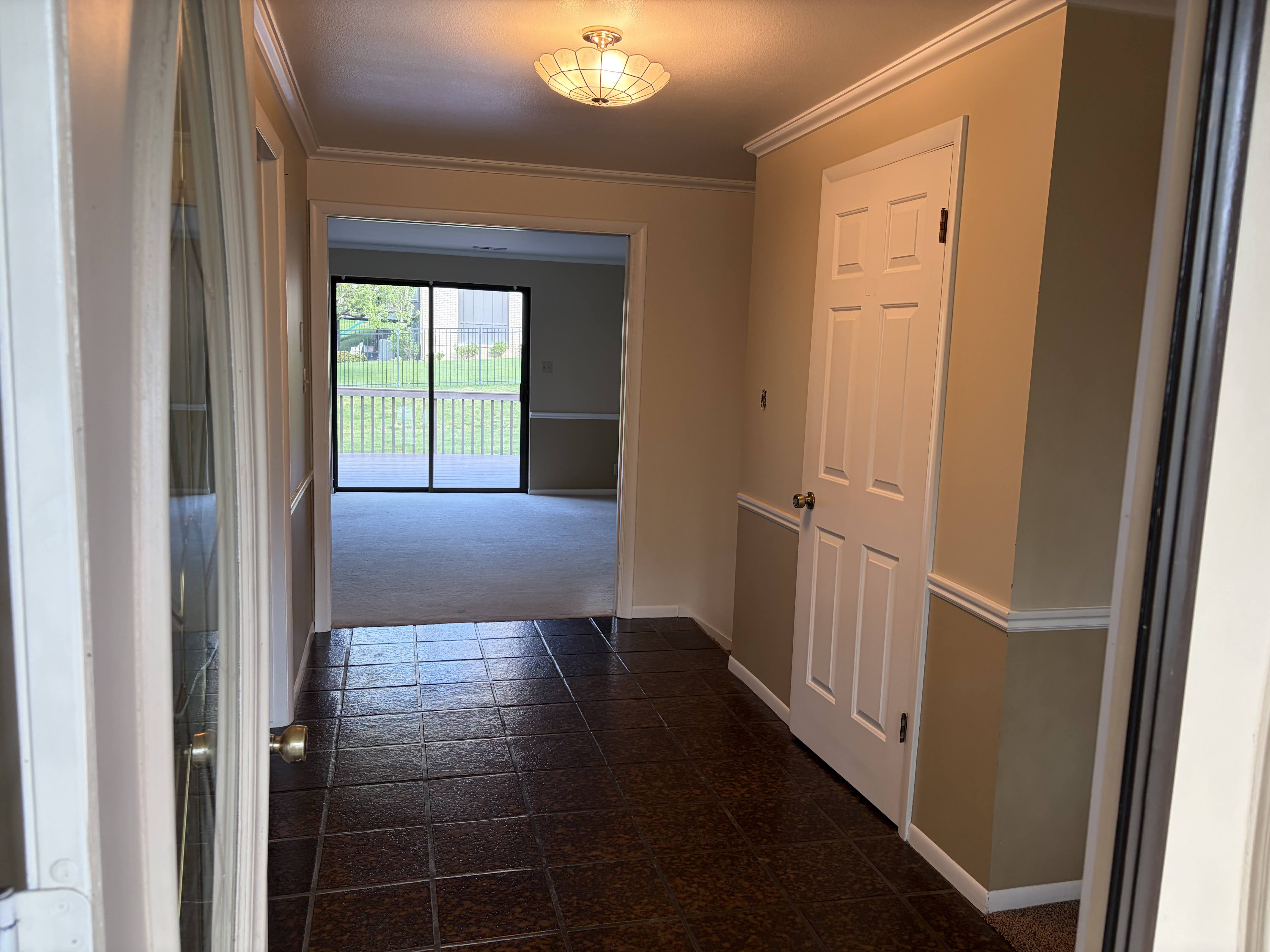 Hallway featuring crown molding and dark colored carpet