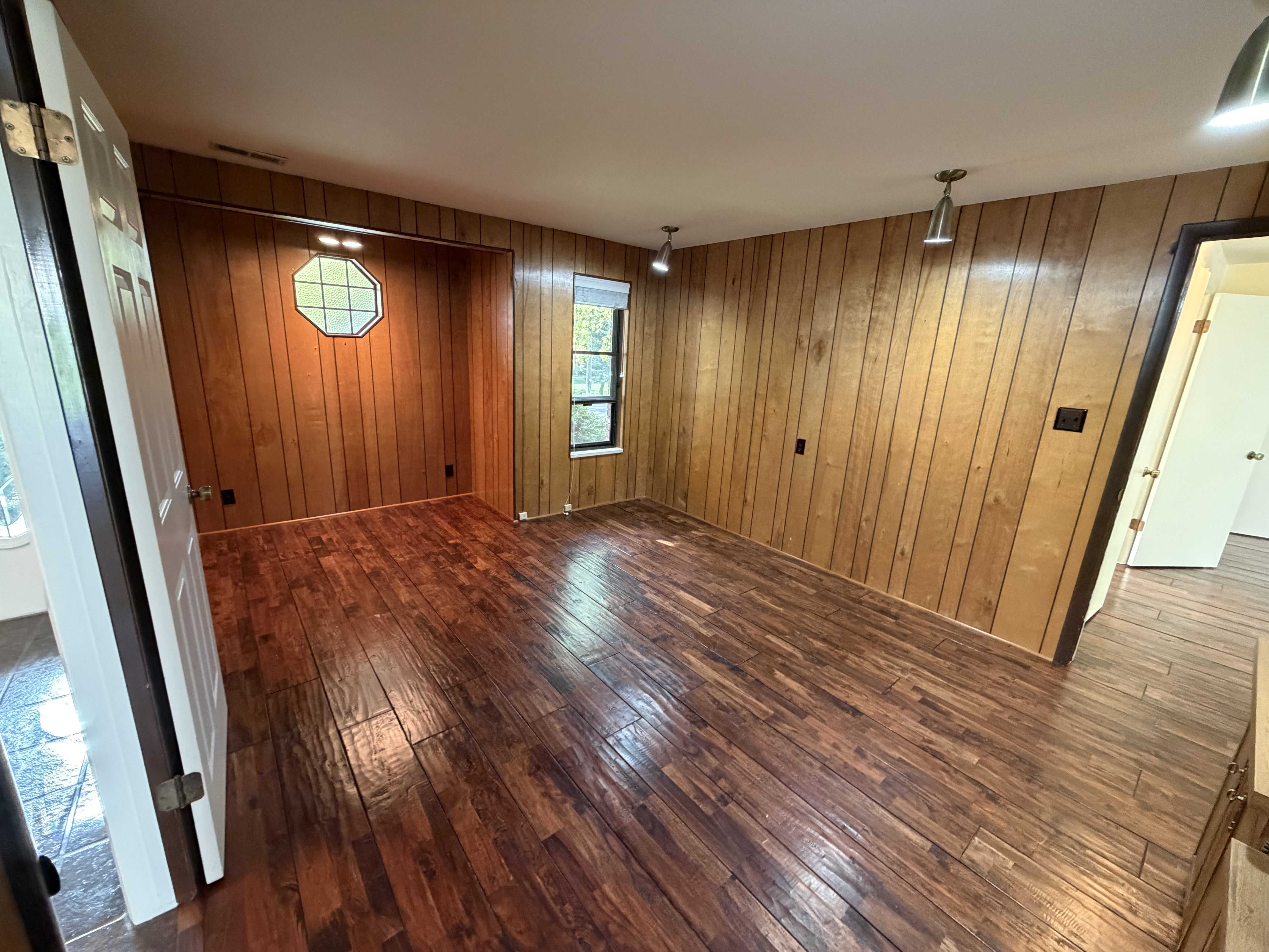 Unfurnished room featuring dark wood-style flooring and wood walls