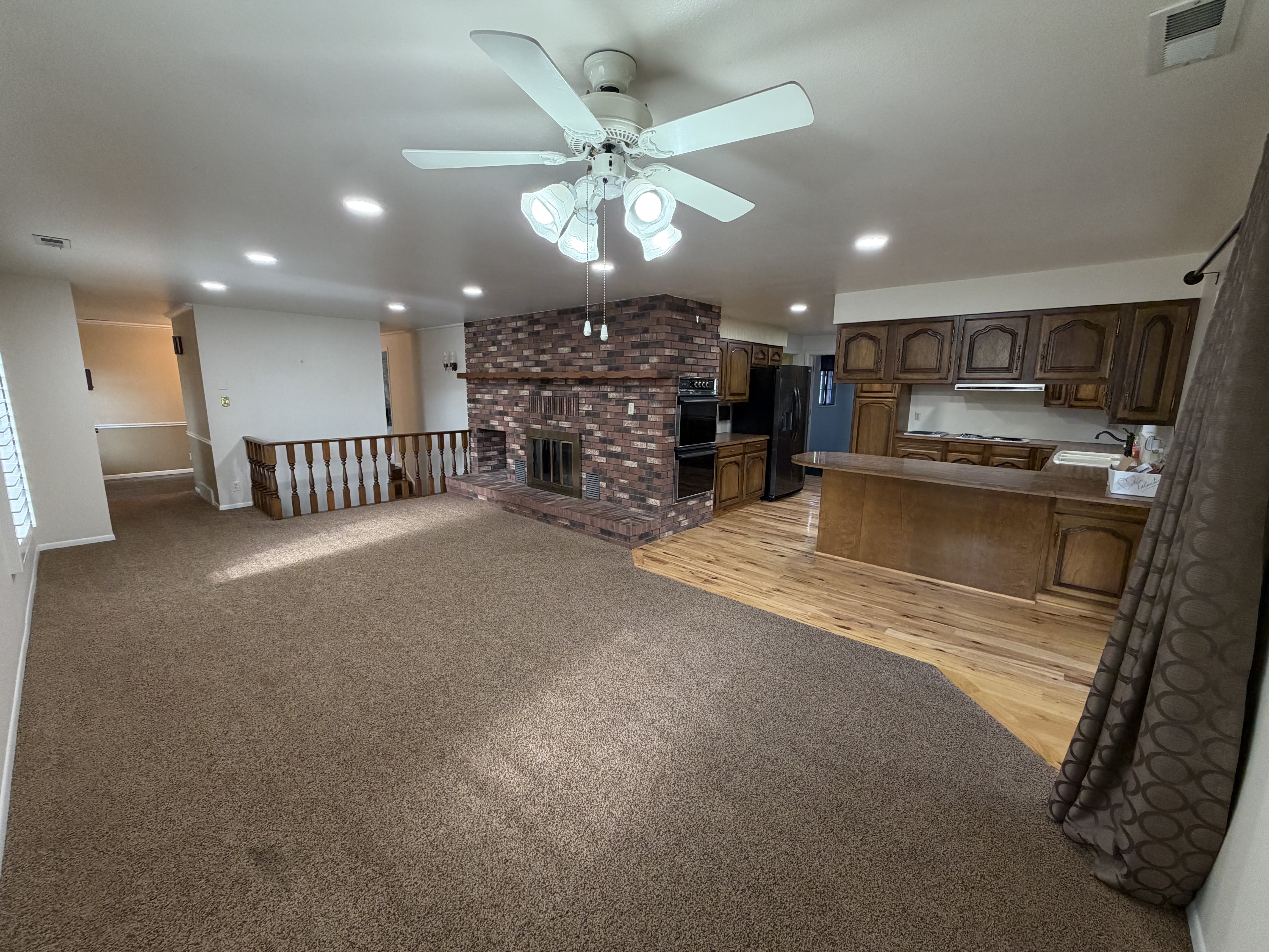 Kitchen featuring a brick fireplace, light colored carpet, open floor plan, recessed lighting, and a ceiling fan