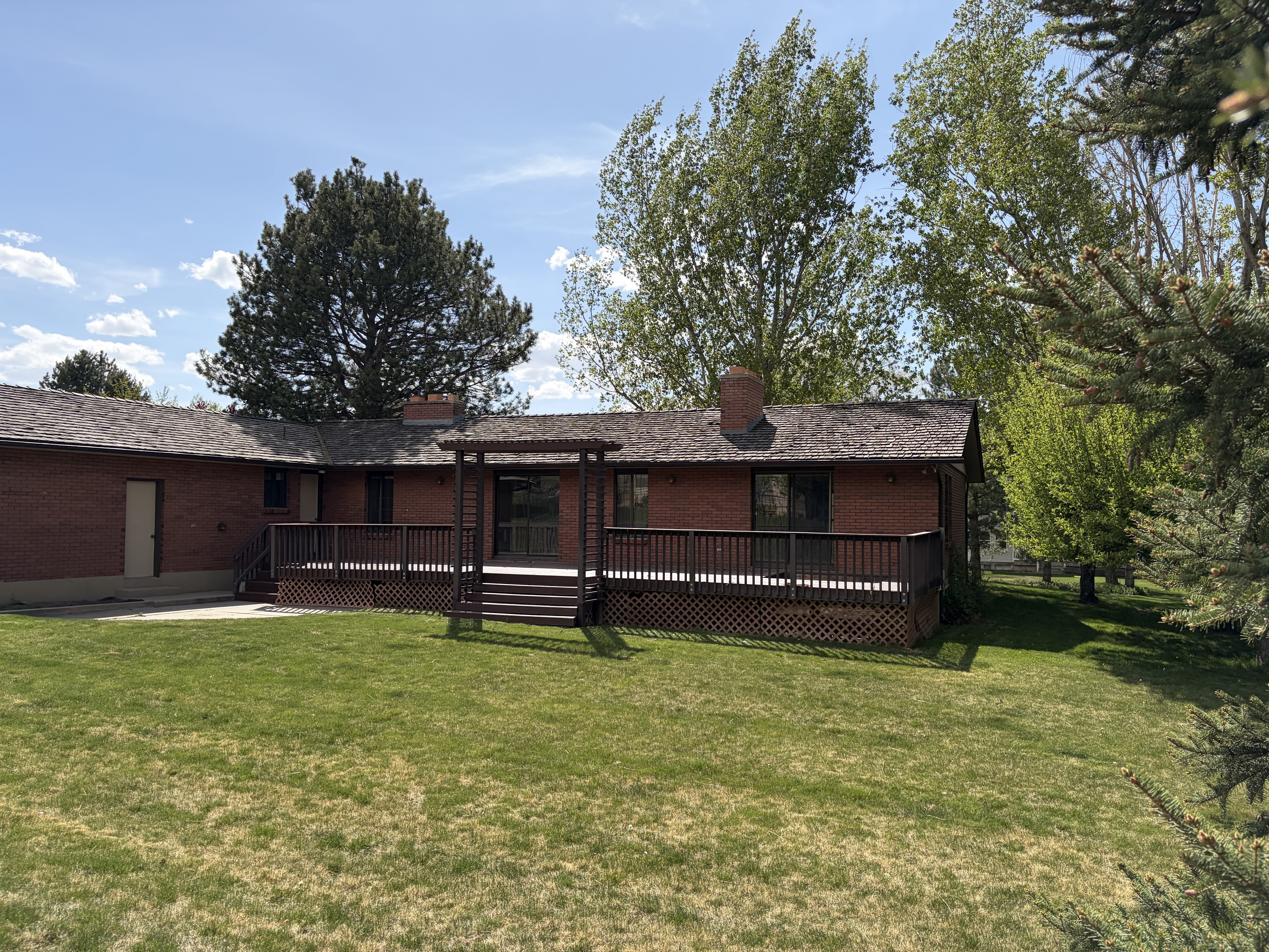Back of property with brick siding, a lawn, a wooden deck, and a chimney