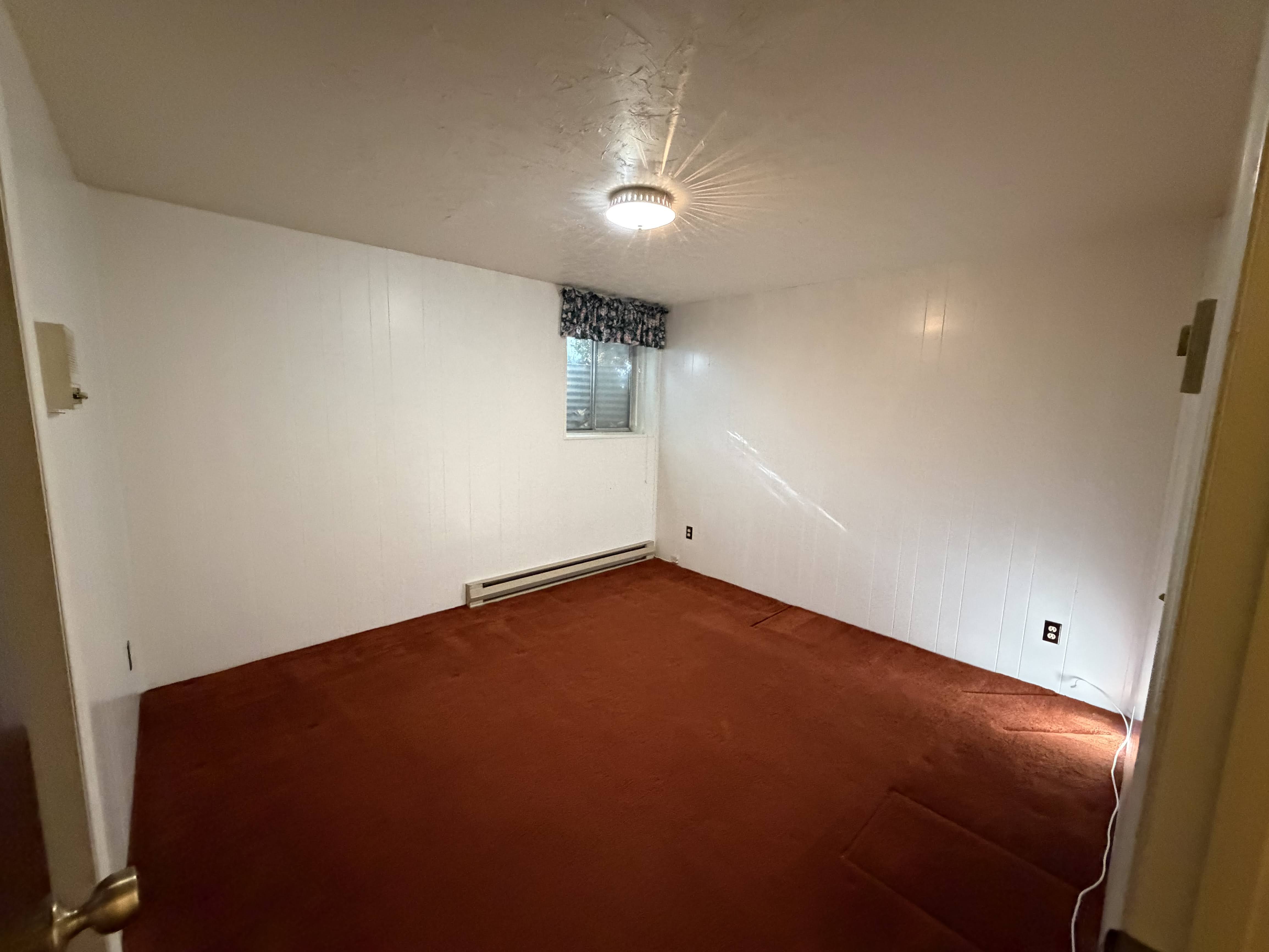 Empty room with dark carpet and baseboard heating