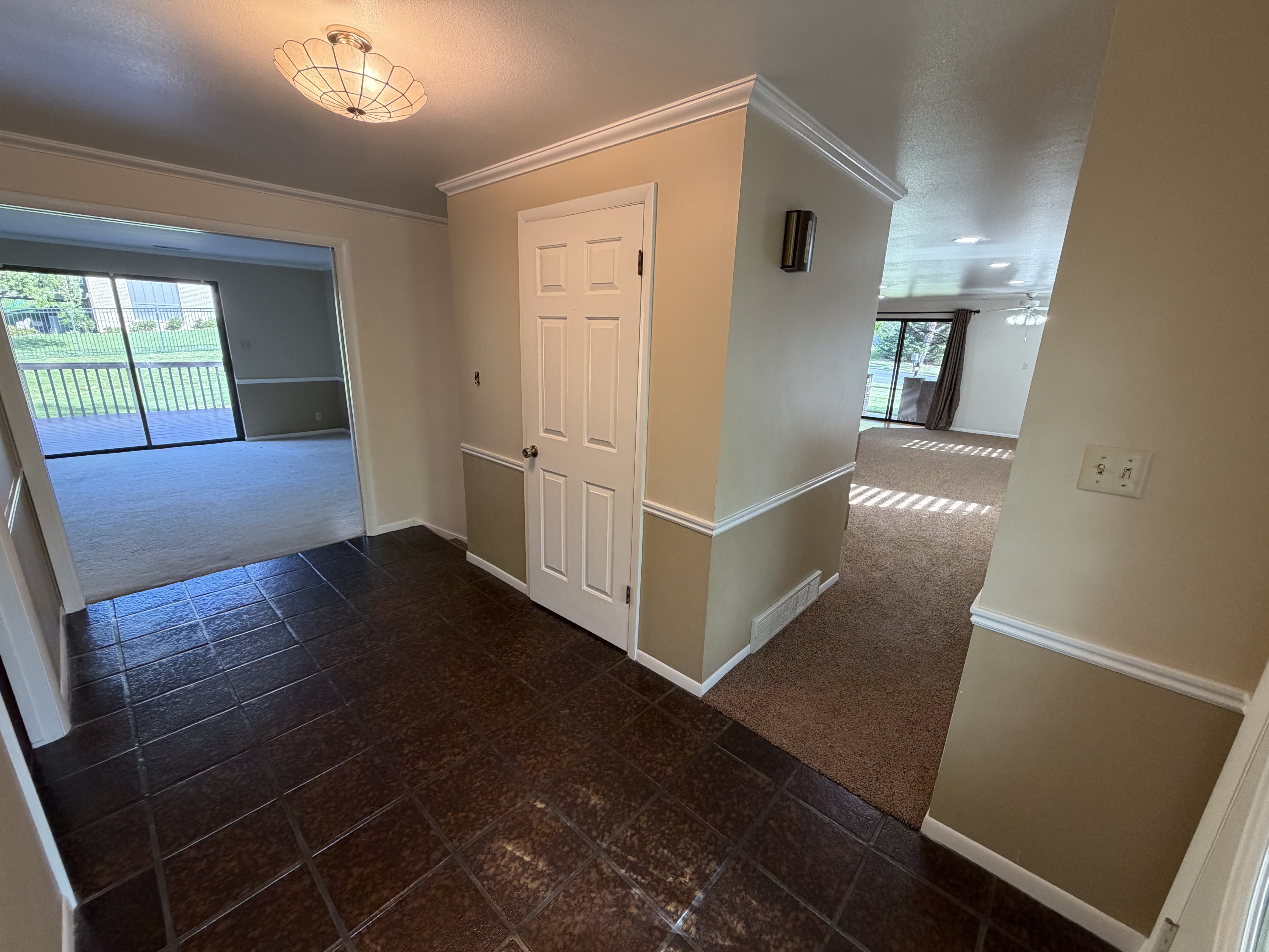 Hall with dark colored carpet, ornamental molding, and plenty of natural light