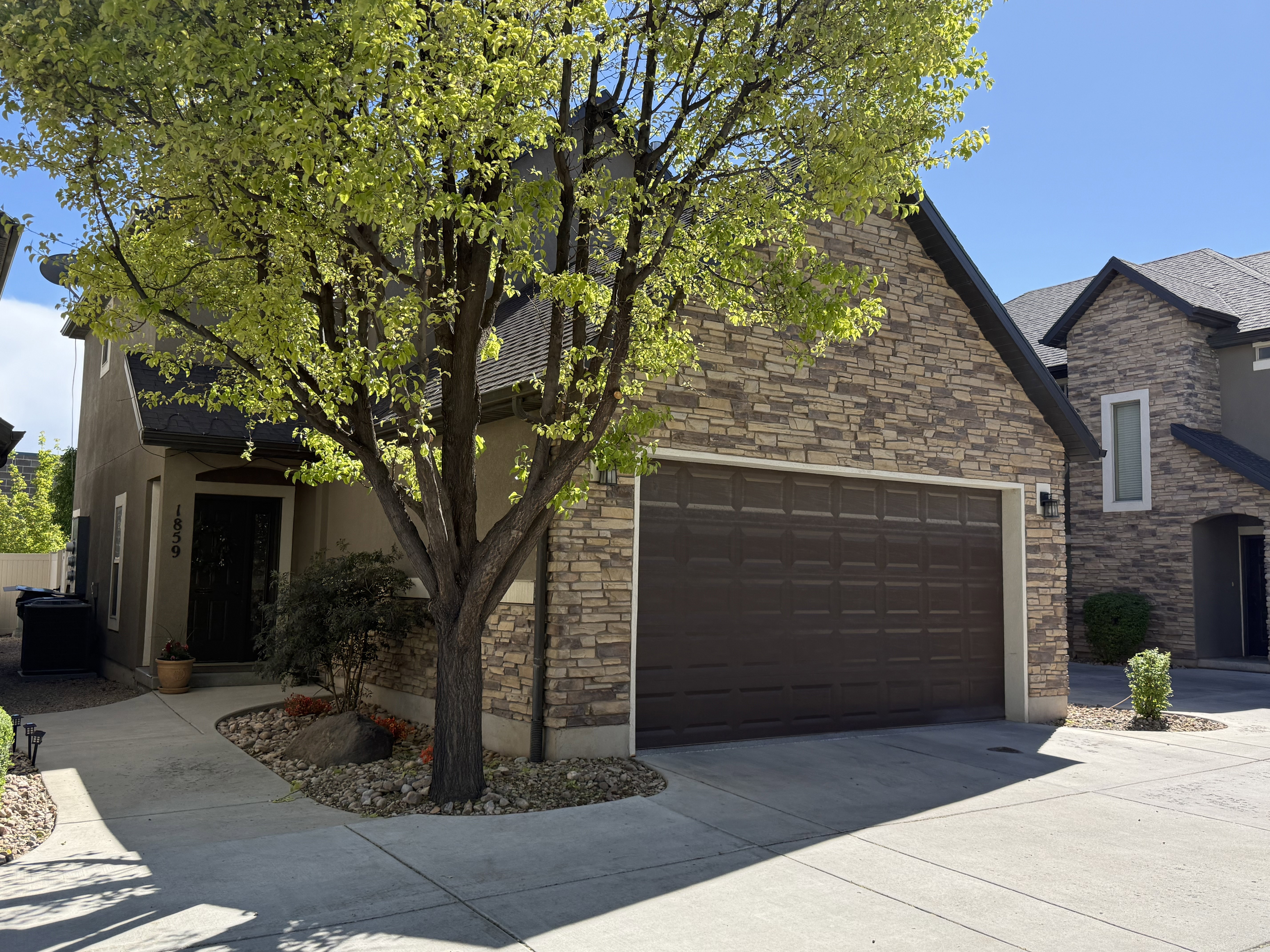 View of front of property featuring driveway, stone siding, a garage, and stucco siding
