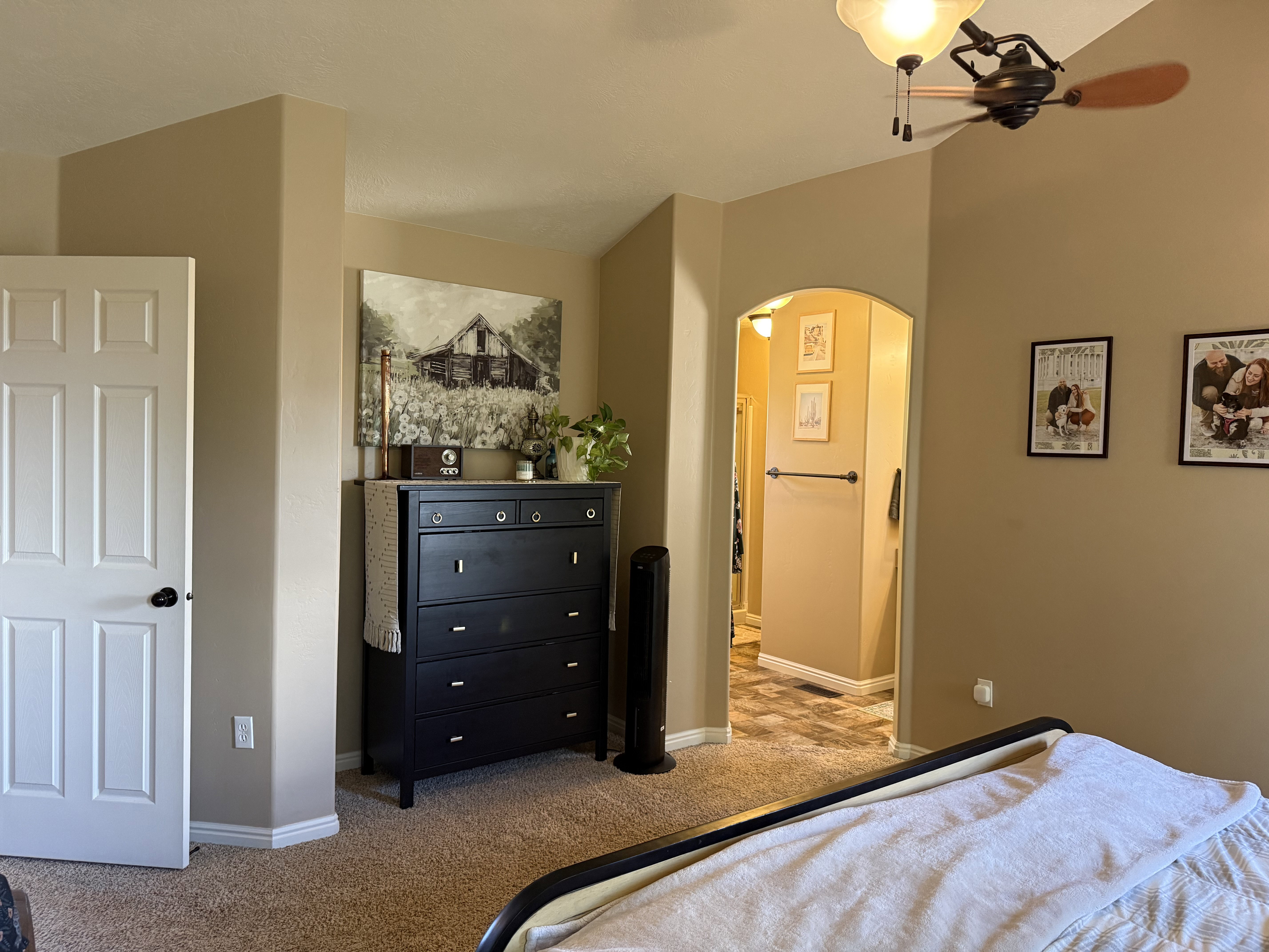 Bedroom featuring arched walkways, light colored carpet, and ceiling fan