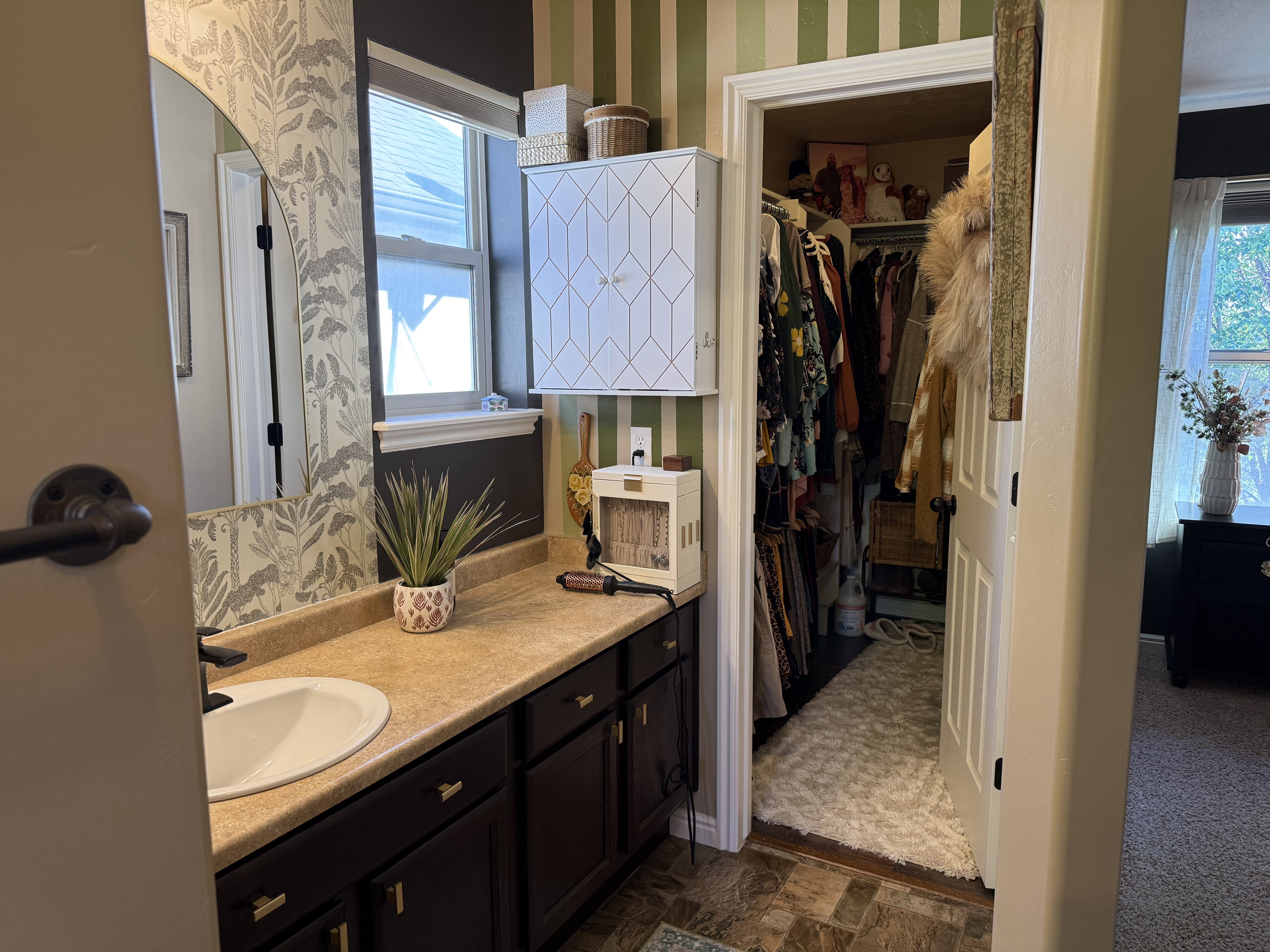 Full bathroom featuring wallpapered walls, vanity, a walk in closet, and dark flooring