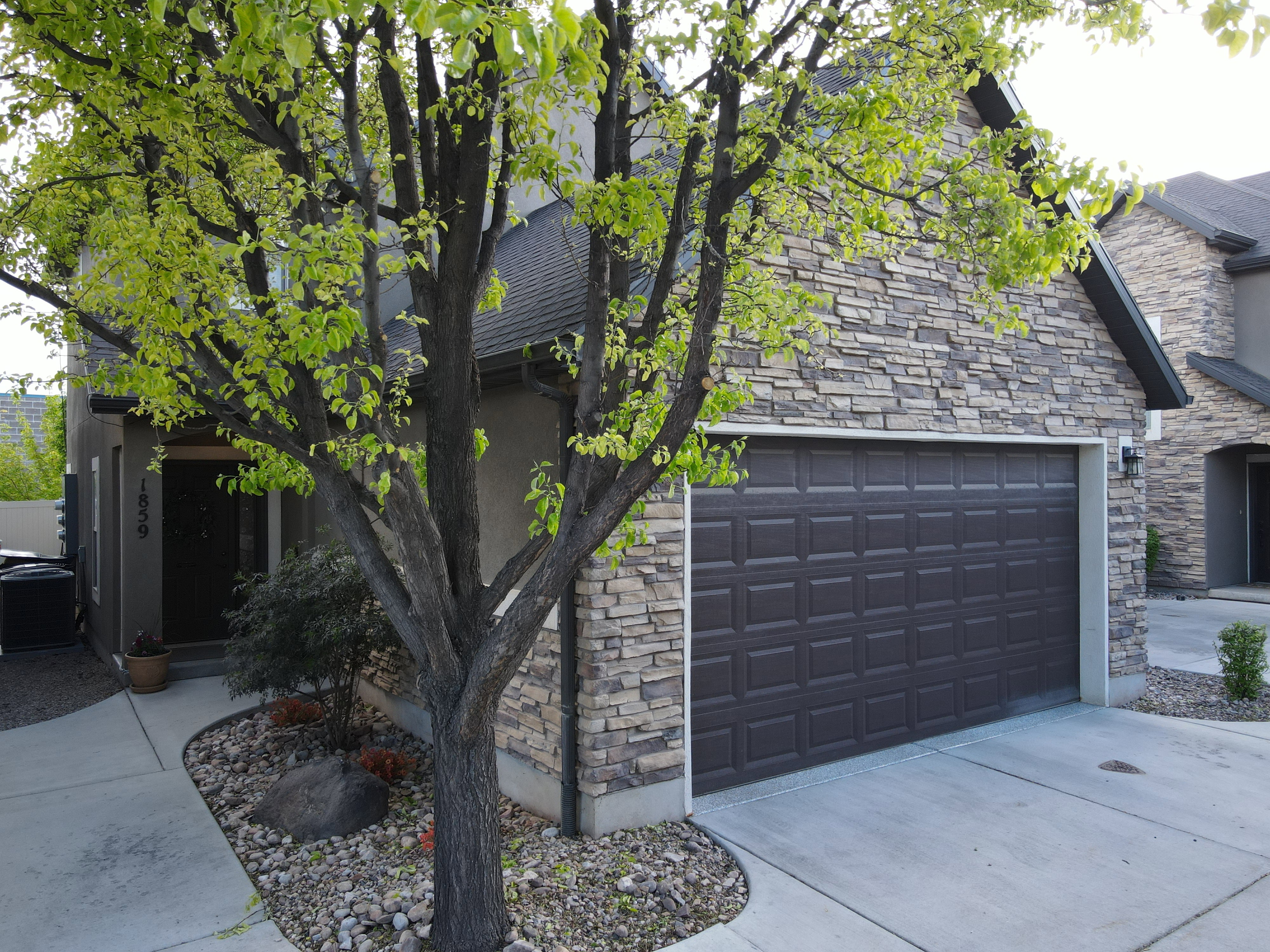 View of side of home featuring stone siding, driveway, and stucco siding