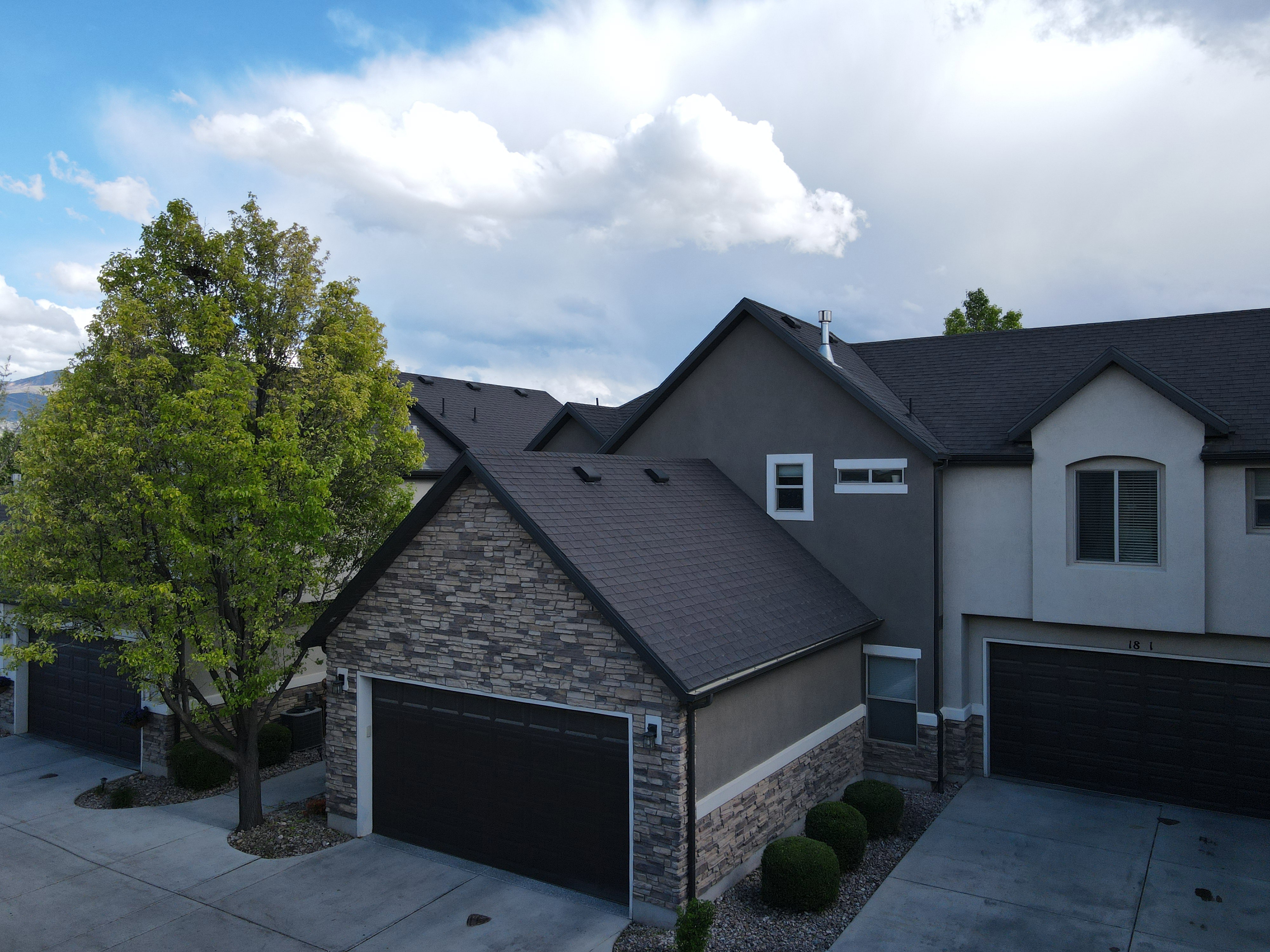 View of front of home featuring stone siding, stucco siding, driveway, and roof with shingles