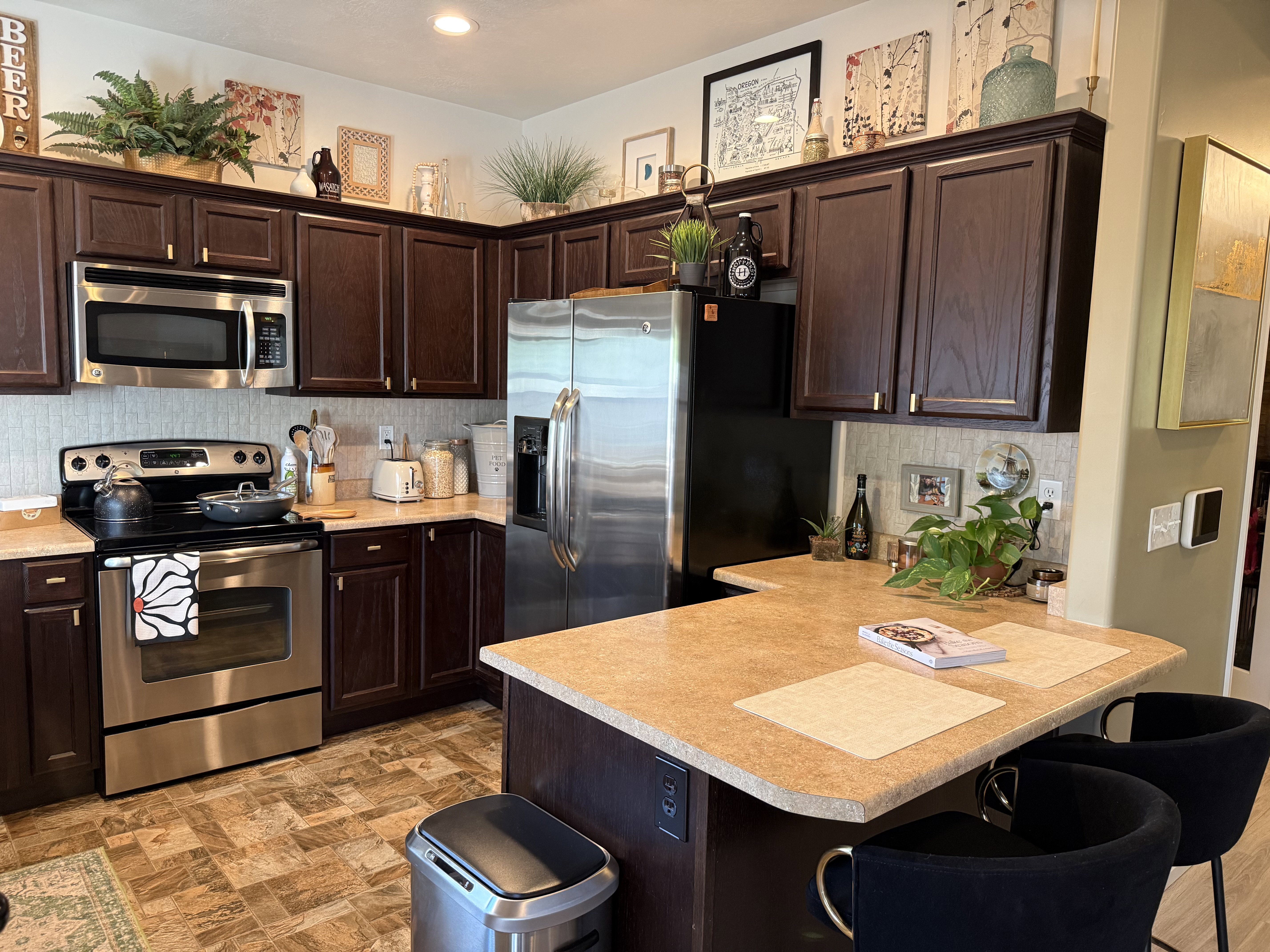 Kitchen with dark wood finish cabinetry, stainless steel appliances, a kitchen breakfast bar, and backsplash