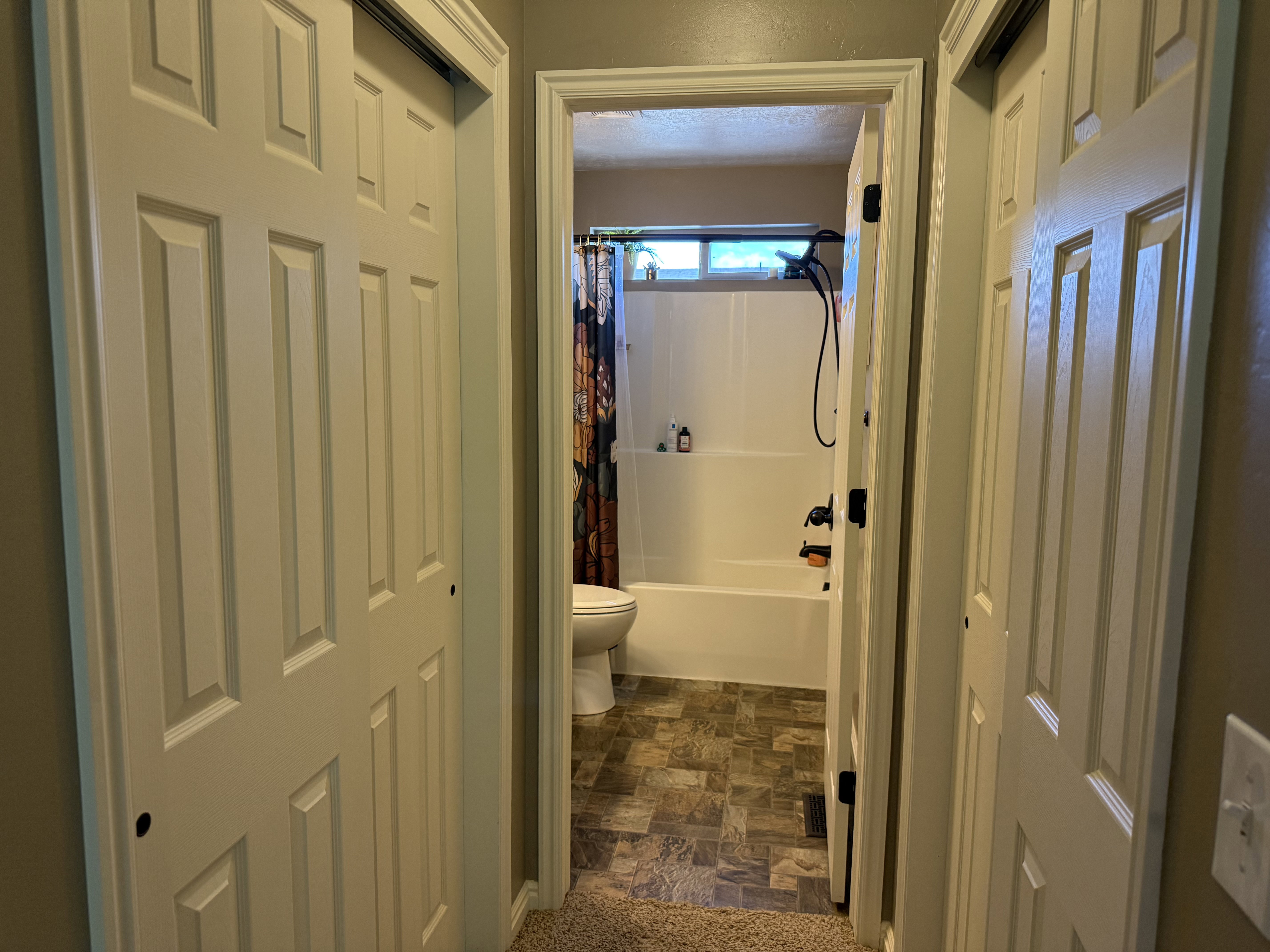 Full bath featuring stone finish floors and shower / tub combo with curtain