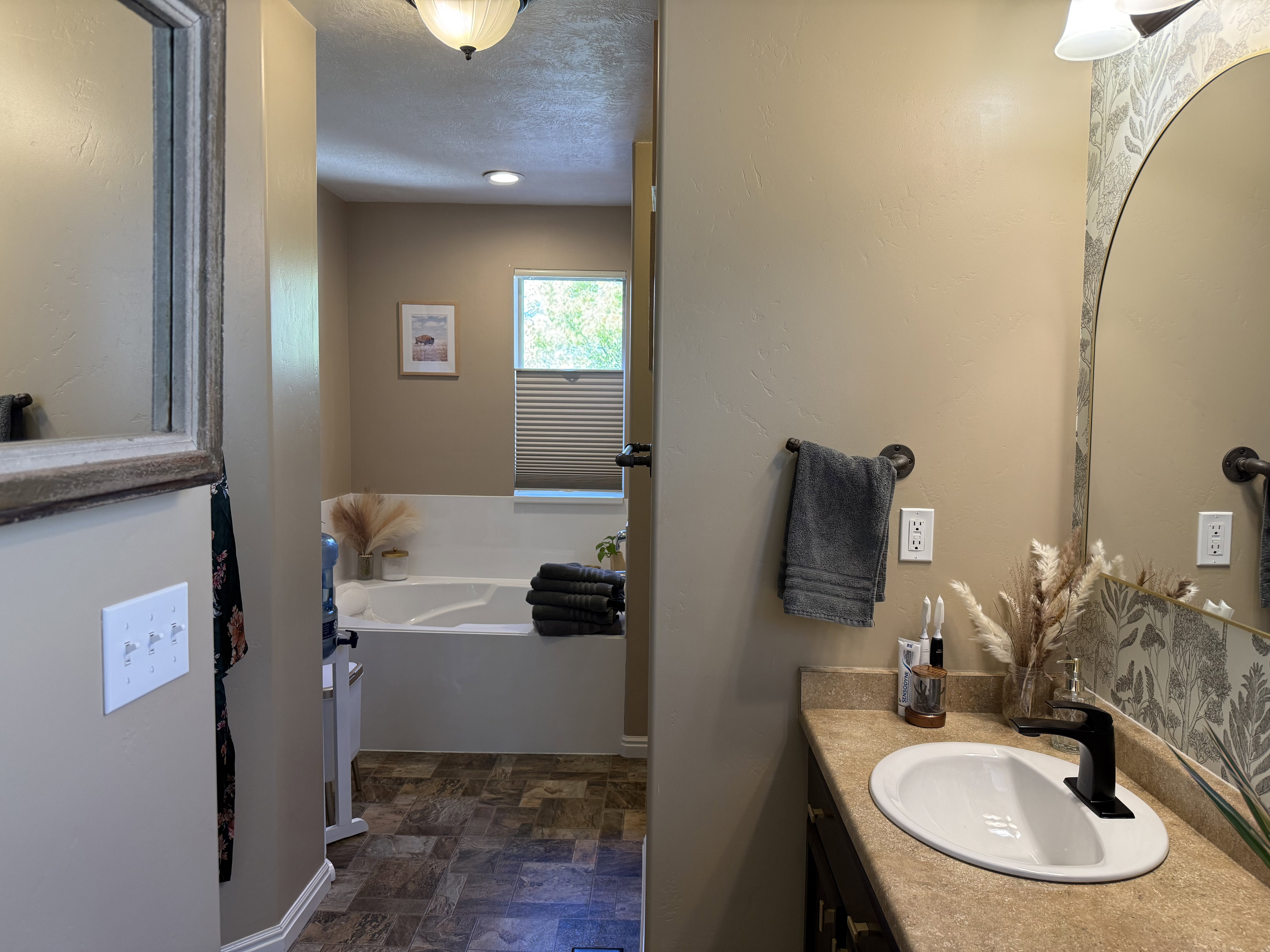 Bathroom with vanity, a bath, stone finish flooring, and a textured ceiling