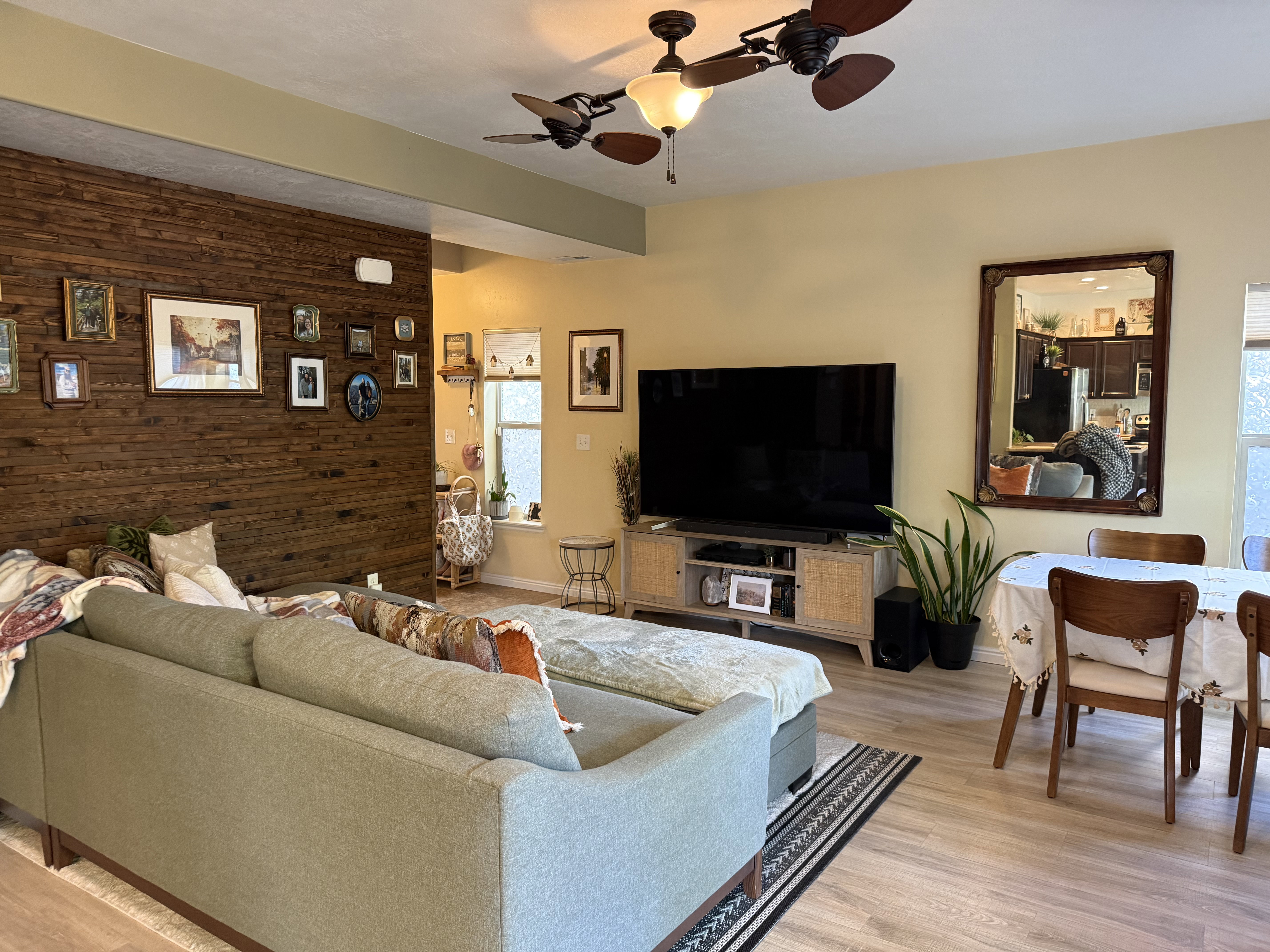 Living area featuring wood walls, ceiling fan, light wood-style floors, and an accent wall