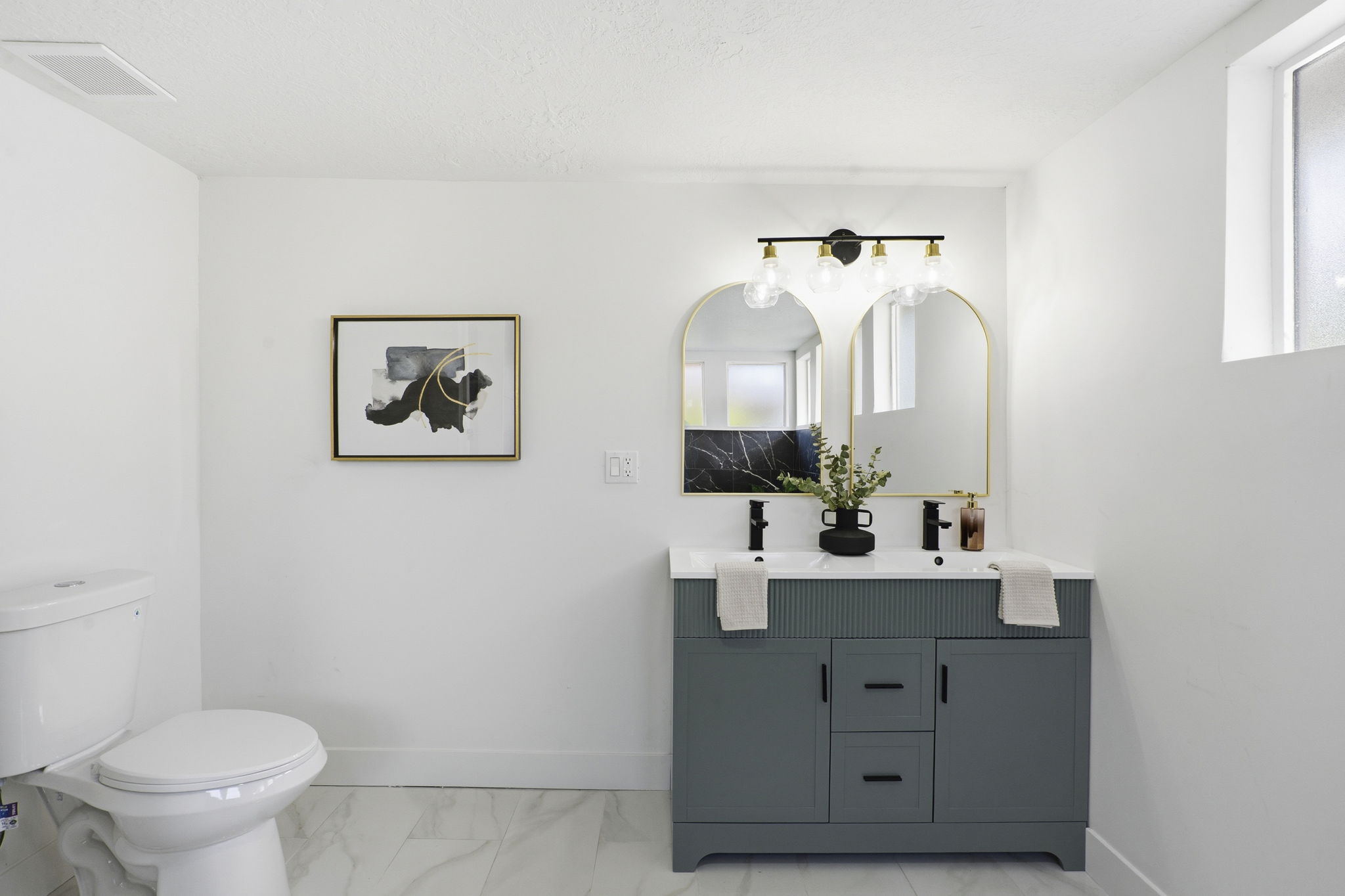 Bathroom with double vanity and light marble finish flooring