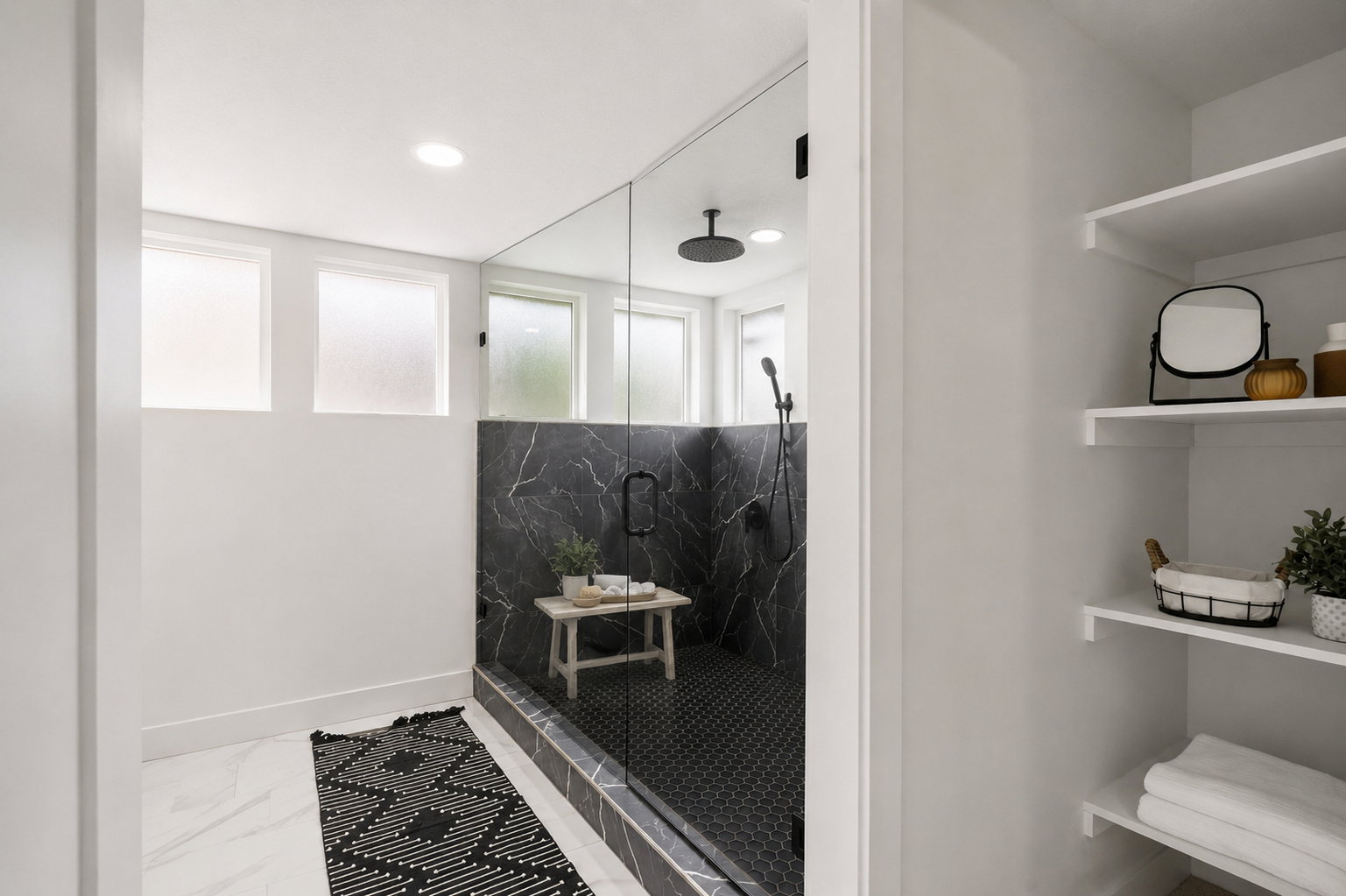 Walk-in shower with clear glass enclosure and black marble-patterned tile