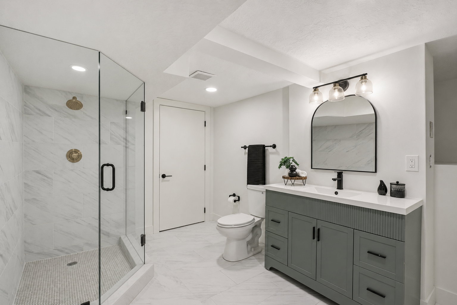 Modern bathroom featuring a glass-enclosed shower with gold-tone fixtures, a built-in shower niche, and white marble-look tile