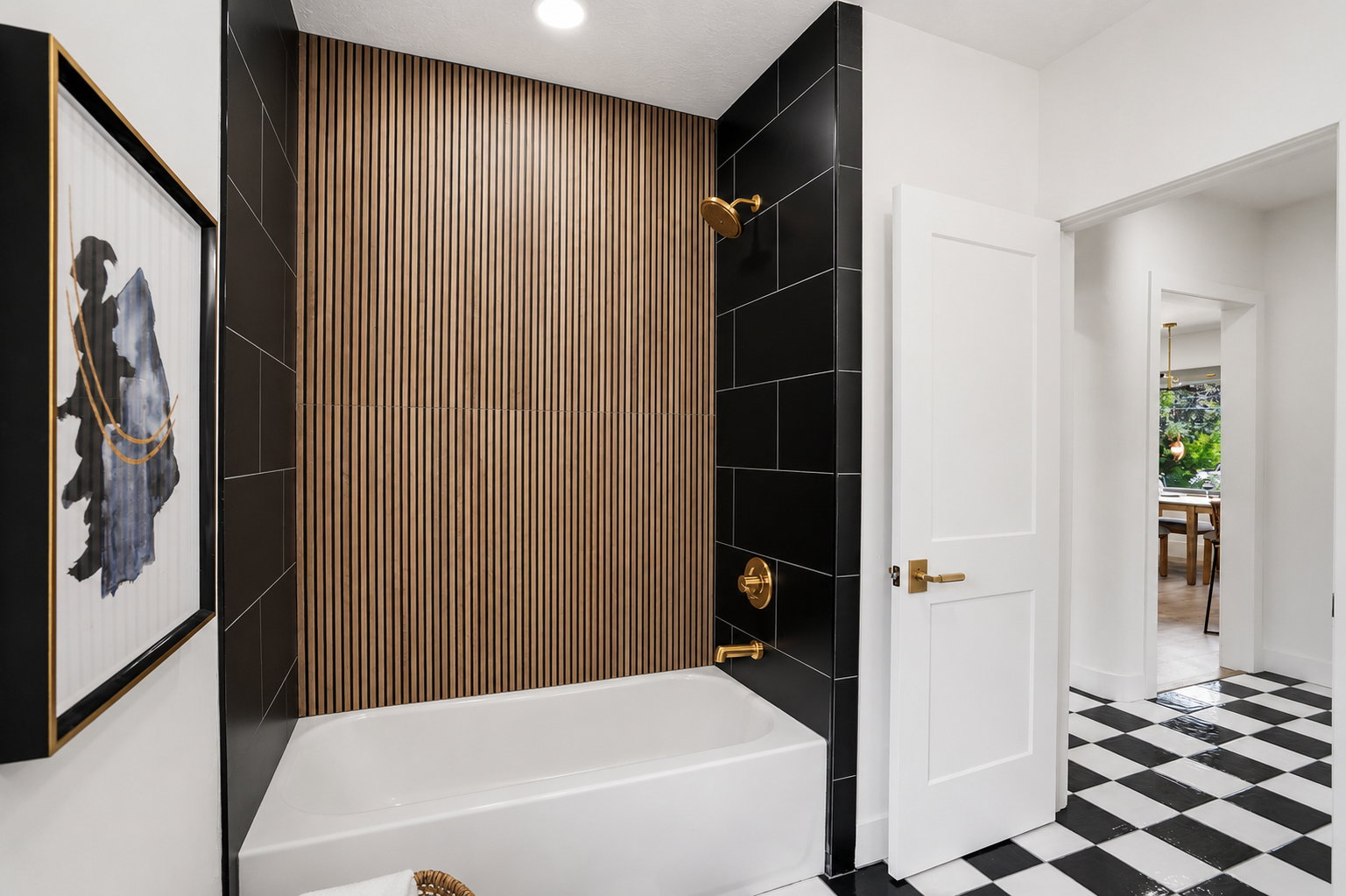 Bathroom with a white bathtub featuring a wood-panel accent wall and black subway tile surround