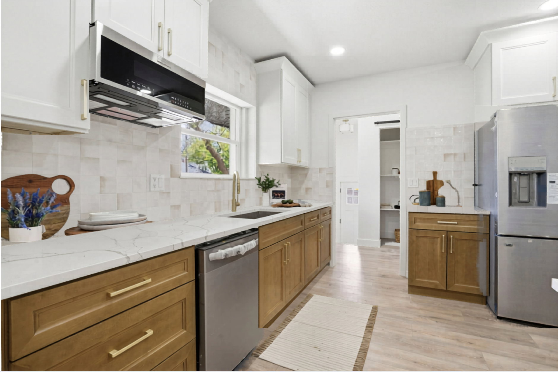 Kitchen with two tone color scheme, stainless steel appliances, light stone counters, light wood-type flooring, and backsplash