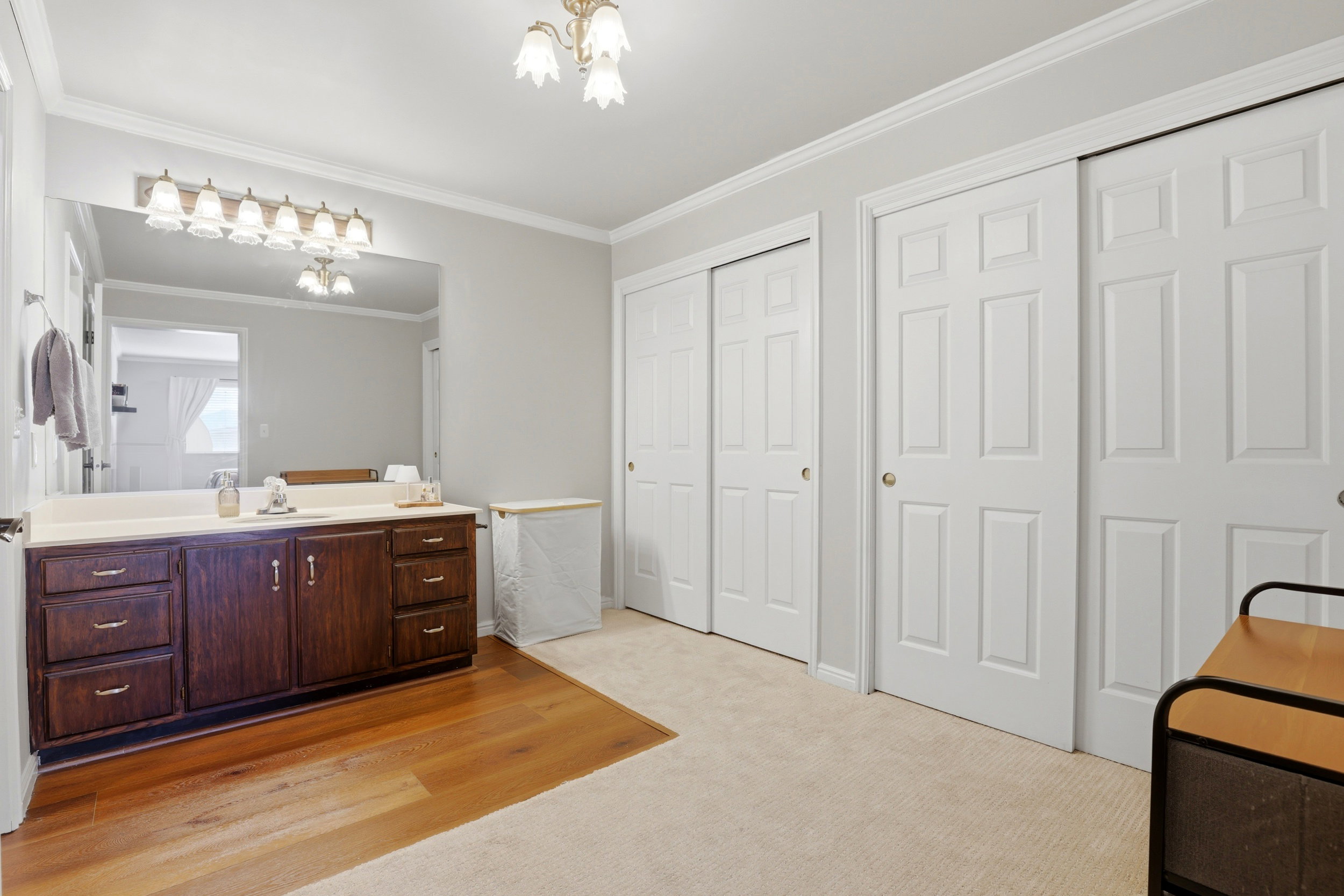 Bathroom featuring vanity, light carpet, a chandelier, ornamental molding, and light wood finished floors
